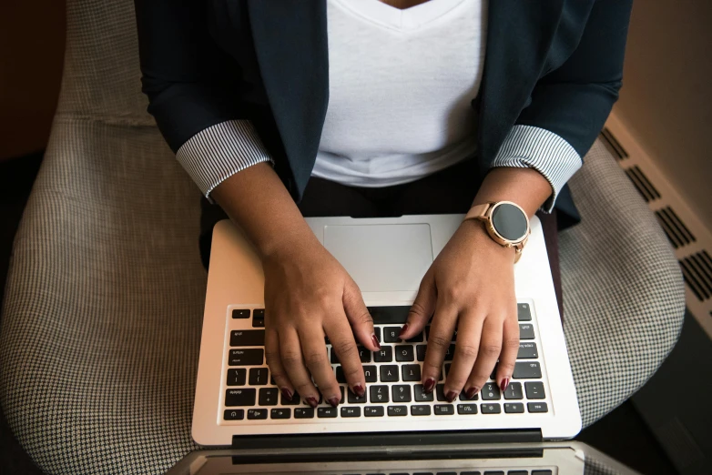 a woman sitting in a chair typing on a laptop, by Carey Morris, pexels, view from above, panel of black, well - dressed, technical