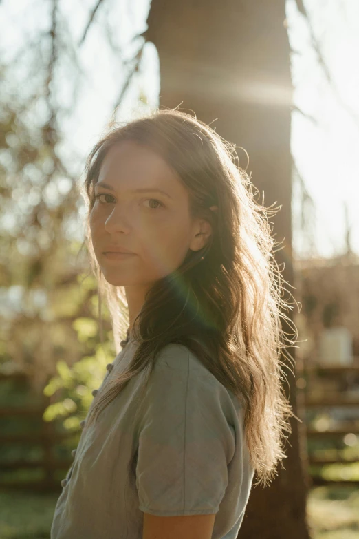 a woman standing in front of a tree, woman with braided brown hair, sun drenched, summer glau, on a pale background