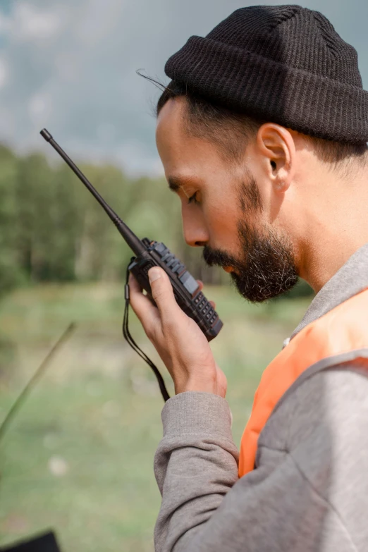 a man in an orange vest holding a walkie talkie, hunting, neck zoomed in, profile pic, promo image