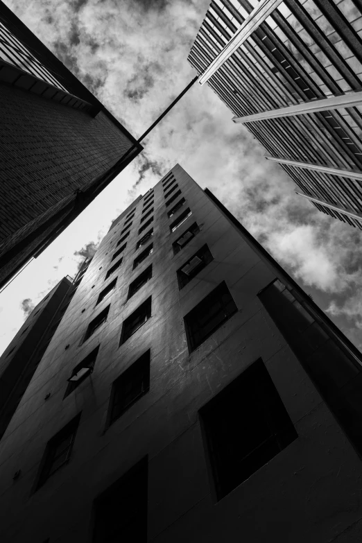 a black and white photo of tall buildings, inspired by André Kertész, unsplash contest winner, low angle!!!!, location [ chicago ( alley ) ], square lines, . dramatic angle