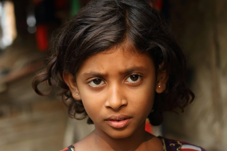 a little girl that is looking at the camera, by Sunil Das, pexels contest winner, hurufiyya, young woman's face, brown skinned, serious expression, taken in the late 2010s