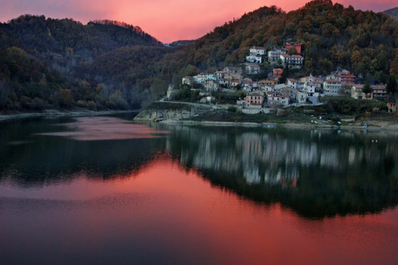 a small town sitting on top of a hill next to a body of water, by Mirko Rački, pexels contest winner, renaissance, pink reflections, sunset in a valley, slide show, intense smoldering