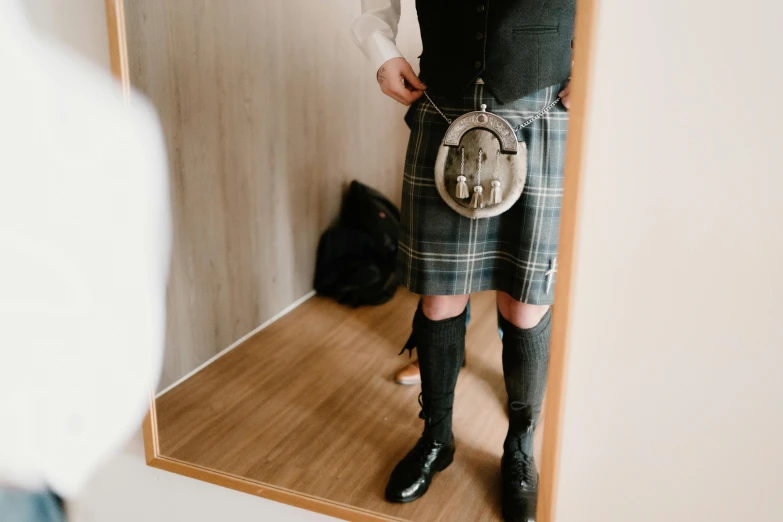 a man in a kilt standing in front of a mirror, pexels contest winner, silver，ivory, holster, february)