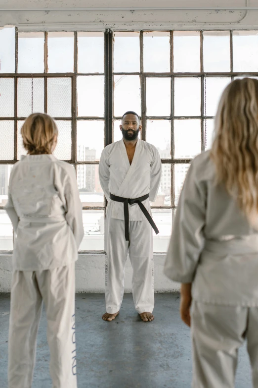 a group of people standing in a room, inspired by Kanō Shōsenin, pexels contest winner, karate outfit, grey, capoeira, overlooking