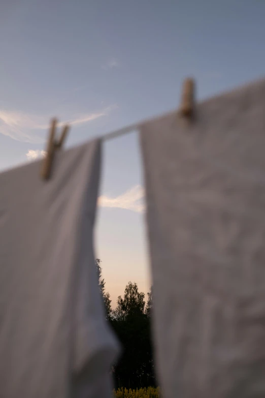 a couple of white towels hanging from a clothes line, unsplash, happening, evening sky, cinematic footage, shot with sony alpha, midsommar