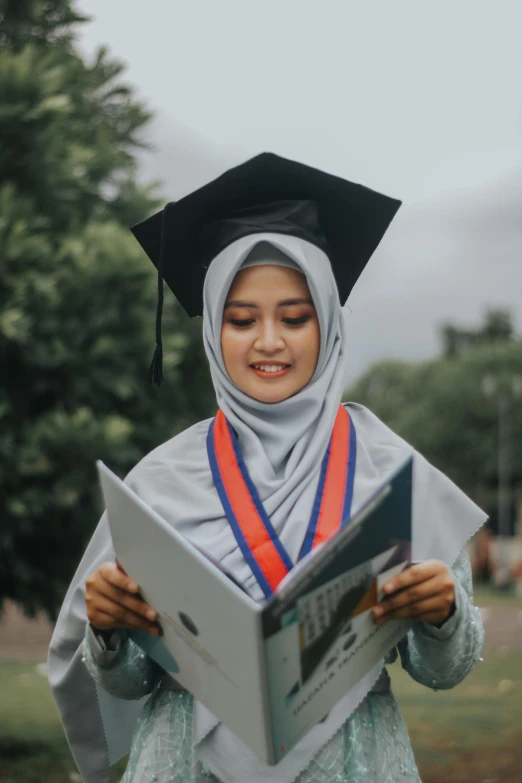 a woman in a graduation gown reading a book, by Basuki Abdullah, pexels contest winner, smirking, gif, religious, instagram picture