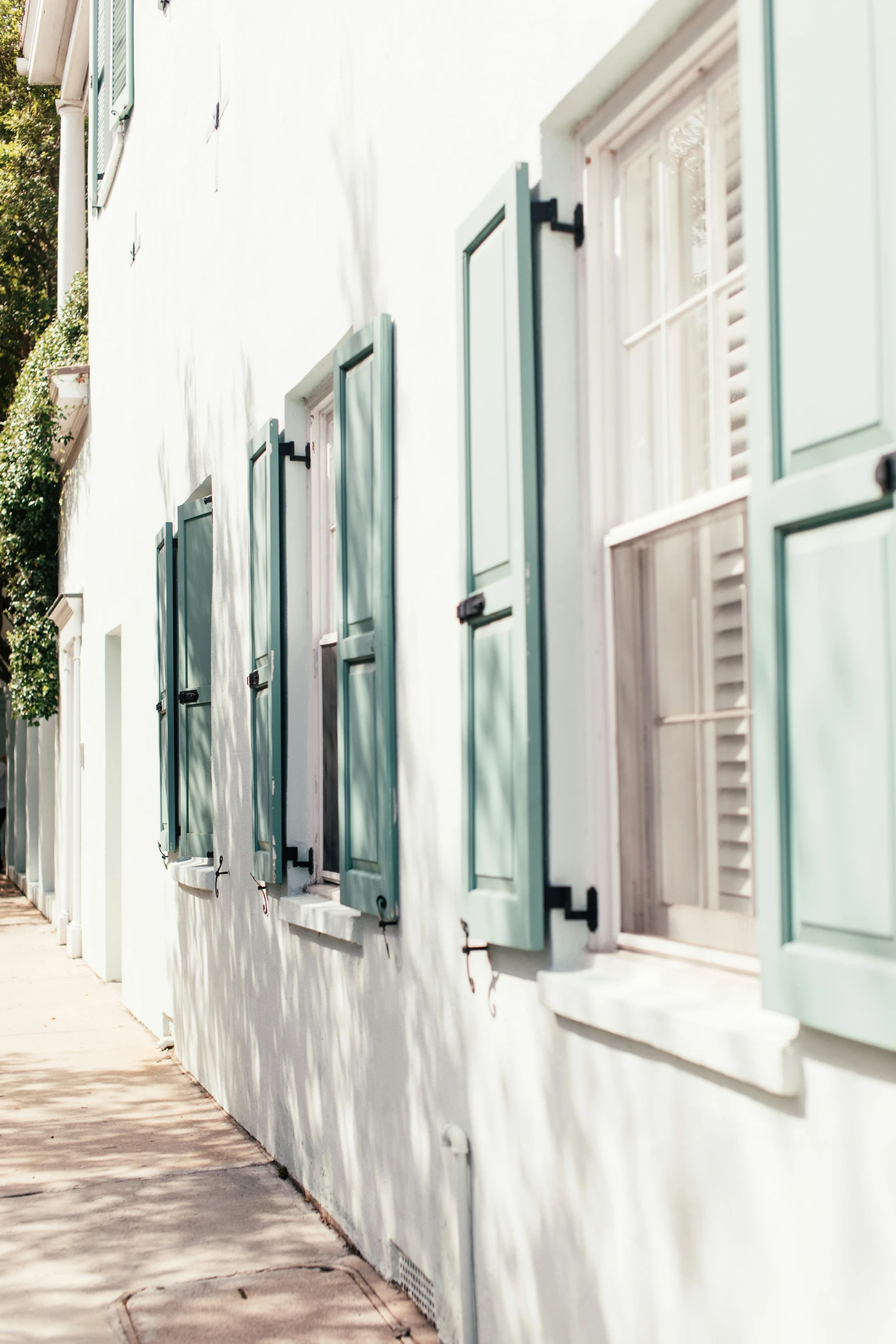 a white building with green shutters next to a sidewalk, by Elizabeth Charleston, trending on unsplash, visual art, aquamarine windows, architectural digest, sunlit windows, 1 7 9 5