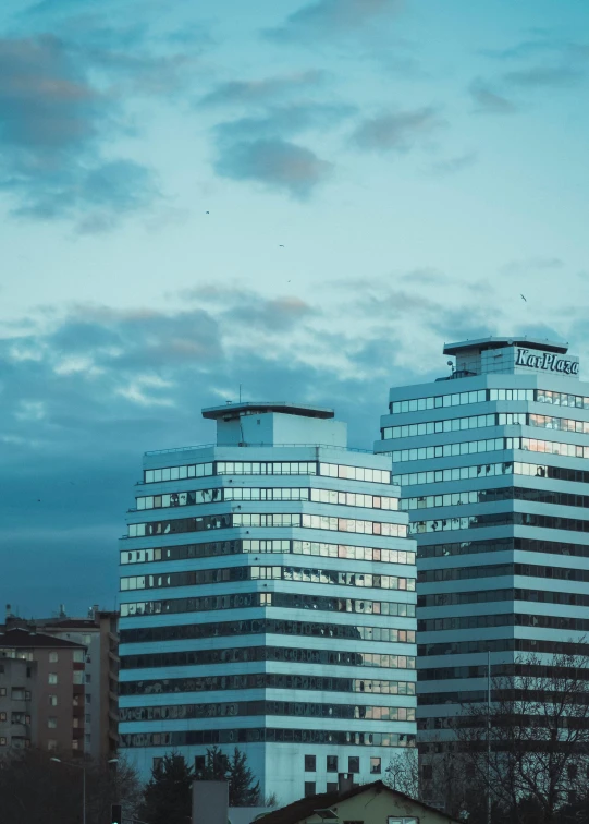 a couple of tall buildings sitting next to each other, a picture, inspired by Elsa Bleda, unsplash contest winner, brutalism, morning. hyperrealism, low quality photo, evening lighting, 1 5 6 6