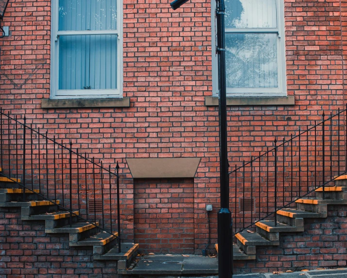 a street light in front of a brick building, inspired by Elsa Bleda, pexels contest winner, arts and crafts movement, impossible stairs, house bolton, neighborhood outside window, buildings covered in black tar
