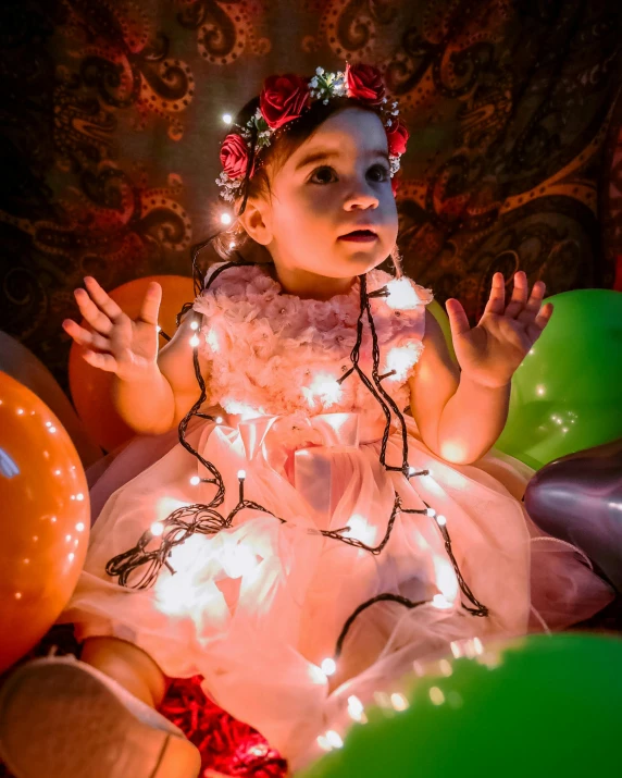 a baby in a dress surrounded by balloons, by Lucia Peka, pexels contest winner, fairy lights, little elf girl, tactile buttons and lights, portrait image