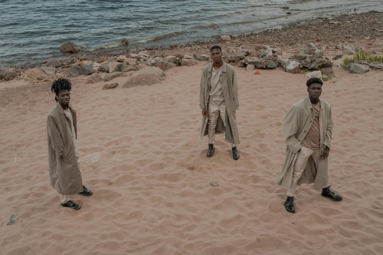 a group of men standing on top of a sandy beach, an album cover, by Caro Niederer, pexels contest winner, afrofuturism, brown robes, actor, modest, rule of three