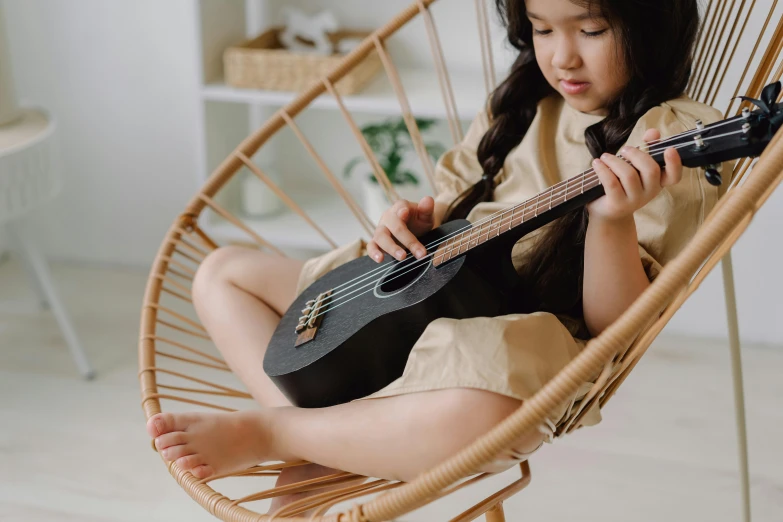 a little girl sitting in a chair with a guitar, pexels contest winner, asian female, carefully crafted, slightly tanned, on a canva