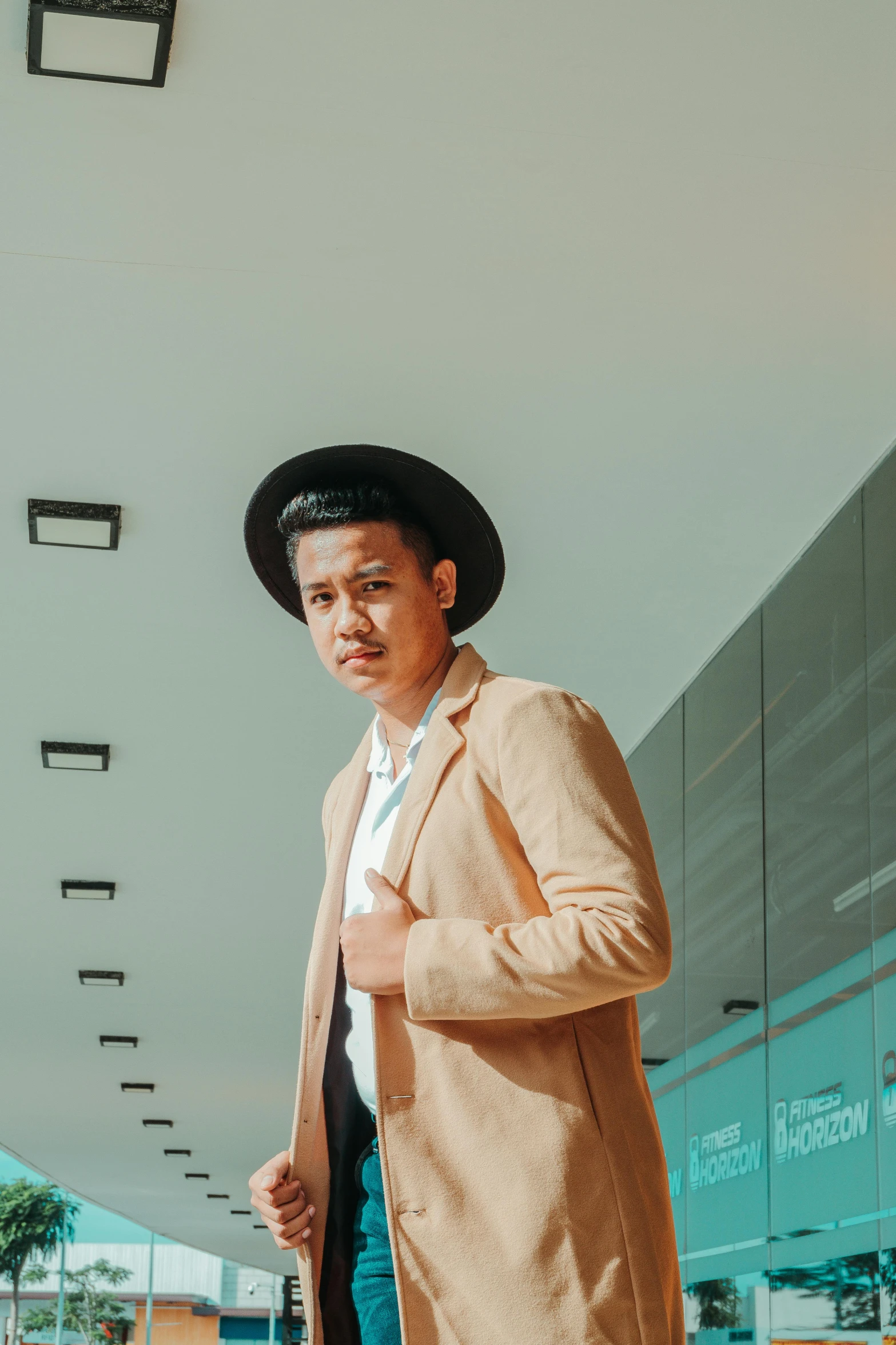 a man in a tan coat and black hat, inspired by Byron Galvez, pexels contest winner, freddy mamani silvestre facade, at a mall, asher duran, formal attire