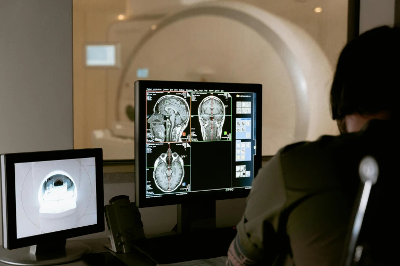 a person sitting at a desk in front of a computer, mri, brain in a vat, 3 heads, cinematic post - processing