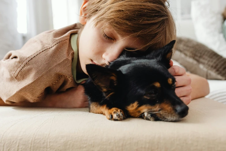 a little boy laying on top of a bed with a dog, pexels contest winner, profile image, relaxing on the couch, 1 4 9 3, hugging each other