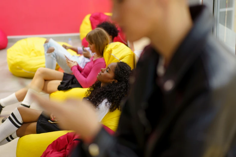 a group of young people sitting on bean bags, by Nina Hamnett, happening, scarlet and yellow scheme, unblur, reading, aida muluneh