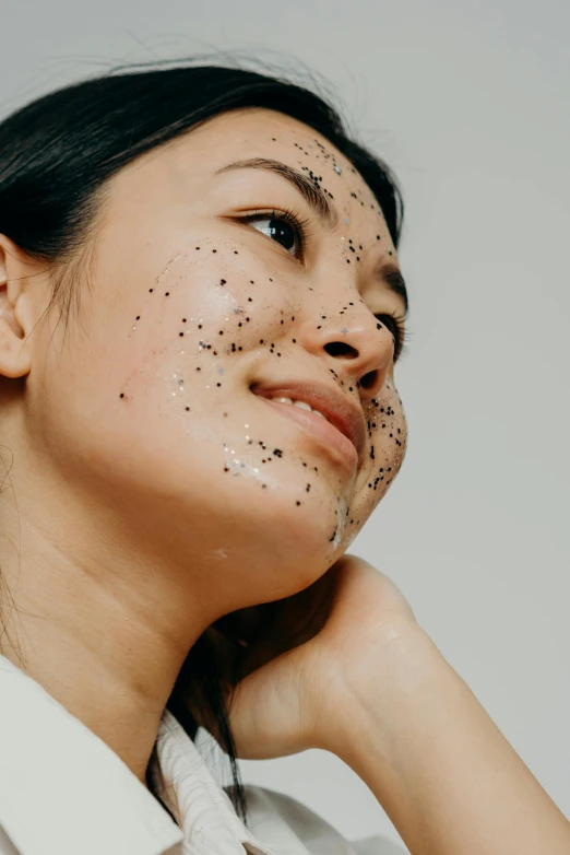 a woman with black spots on her face, trending on pexels, textured base ; product photos, asian, starry, body and face