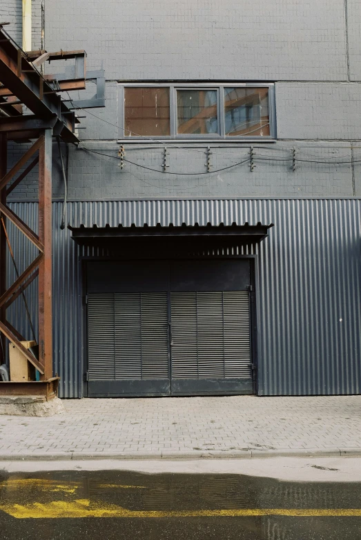 a motorcycle parked in front of a building, metal shutter, dark warehouse, iron cladding, ignant