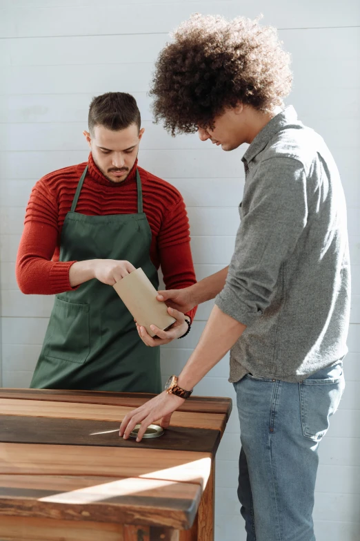 a couple of men standing next to each other in a kitchen, trending on pexels, renaissance, holding wood saw, giving gifts to people, thumbnail, a green