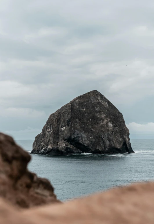 a large rock in the middle of a body of water, renaissance, overlooking the ocean, overcast skies, high-quality photo, slide show