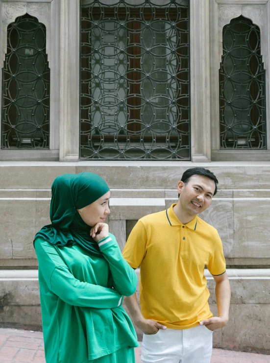 a man and a woman standing in front of a building, inspired by Ismail Acar, pexels contest winner, hurufiyya, yellow and green, wearing polo shirt, national gallery, candid photo