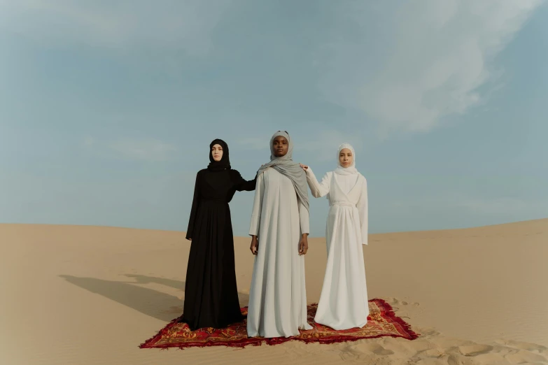 a group of three people standing on top of a desert, an album cover, unsplash contest winner, hurufiyya, religious robes, ☁🌪🌙👩🏾, three women, [ theatrical ]