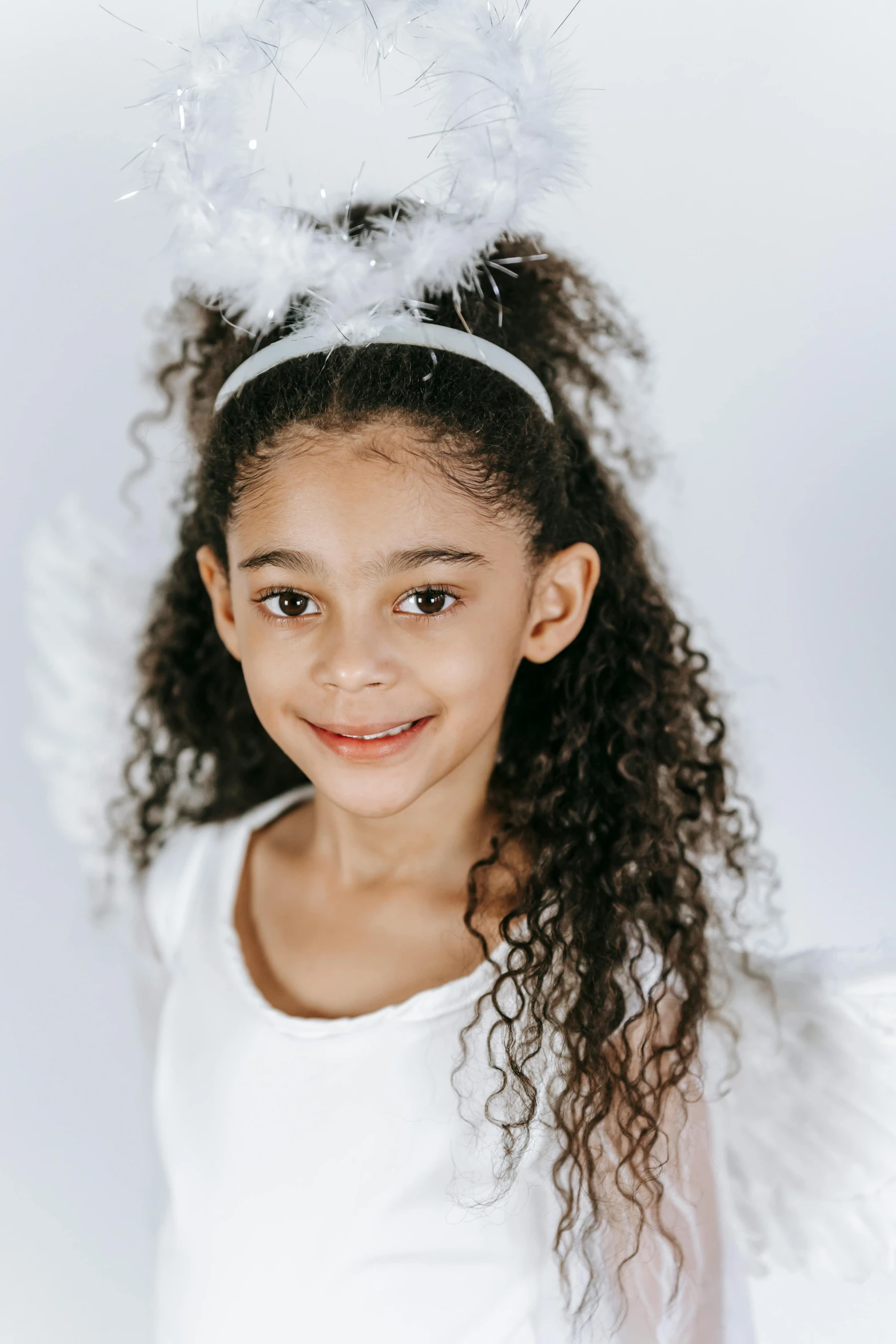 a little girl wearing a white angel costume, inspired by Marie Angel, mixed race, swirly curls, official product photo, pearlescent white