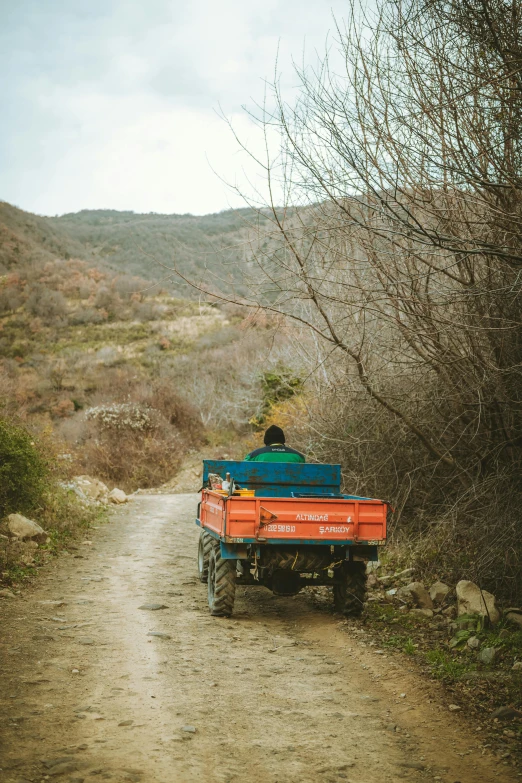 a man riding on the back of a red truck down a dirt road, by Elsa Bleda, trending on unsplash, cyprus, 2 5 6 x 2 5 6 pixels, mine cart, uttarakhand