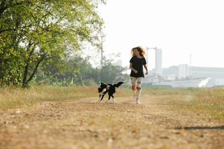 a little girl running with a dog on a dirt road, by Julia Pishtar, happening, in a city park, profile image, black, small