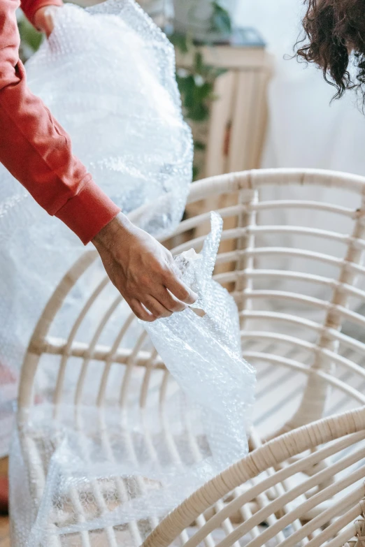 a woman unpacking a chair in a living room, pexels contest winner, plasticien, translucent material, texture detail, wicker chair, bubble