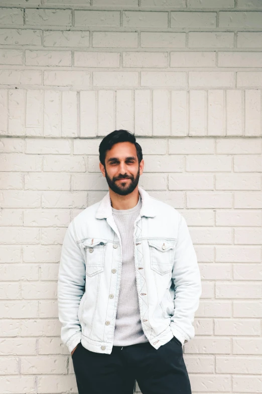 a man standing in front of a white brick wall, short beard, joel torres, jean jacket, transparent background