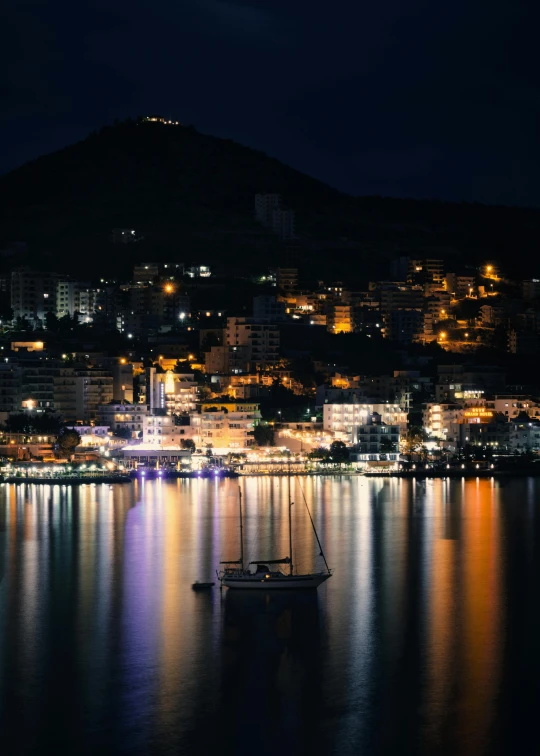 a large body of water with a boat in it, by Julia Pishtar, pexels contest winner, night cityscape, split lighting, highly reflective, telephoto long distance shot