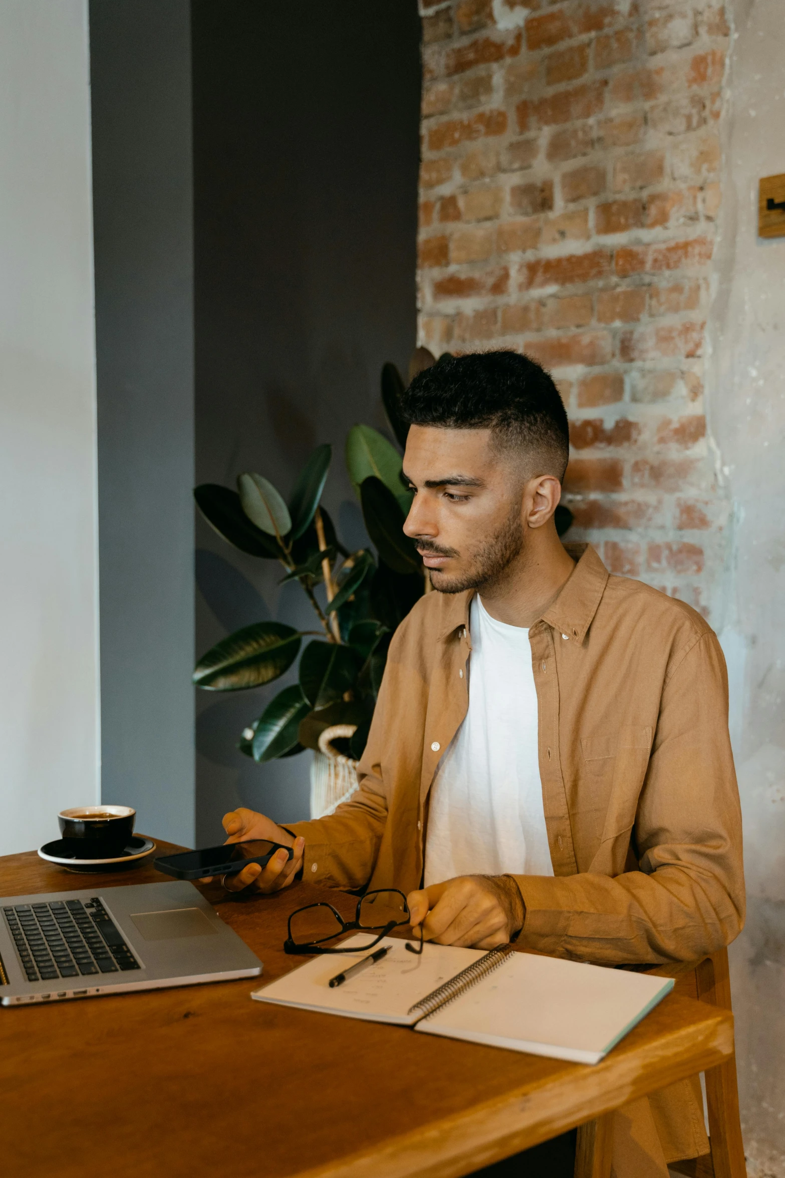 a man sitting at a table with a laptop, trending on pexels, looking straight, brown, young male, ismail