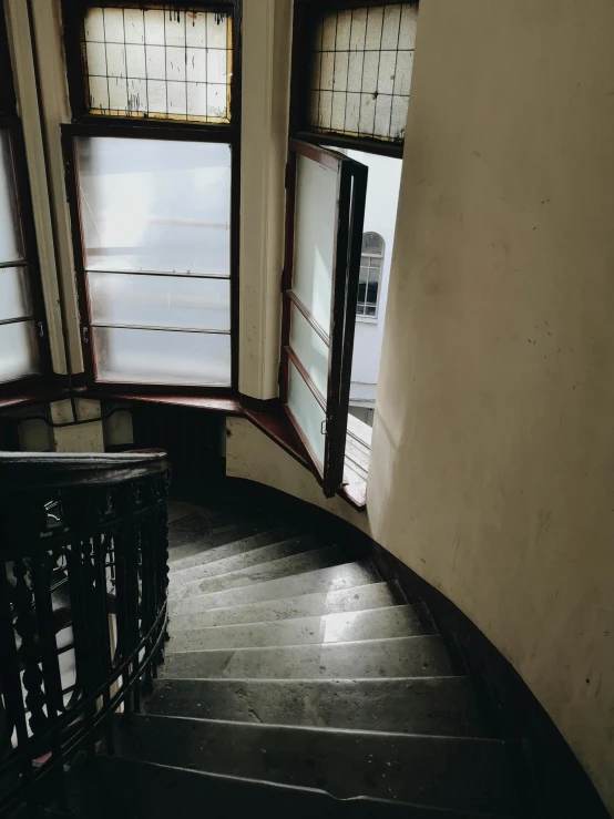 a spiral staircase going up to the top of a building, inspired by André Kertész, unsplash contest winner, art nouveau, bay window, low quality photo, shadow filled room with gloomy, high view