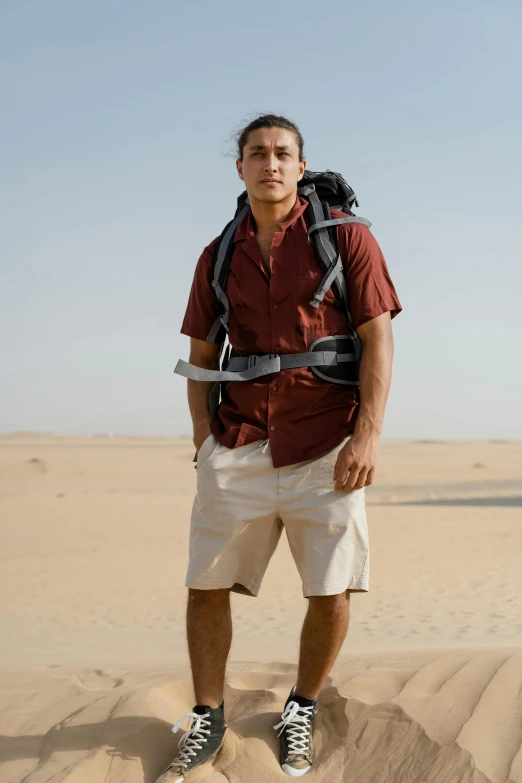 a man standing in the middle of a desert, a man wearing a backpack, maroon and white, lean man with light tan skin, cargo shorts
