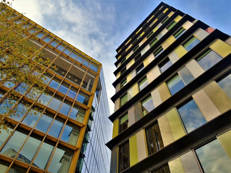 a couple of tall buildings next to each other, a photo, unsplash, modernism, yellow and green scheme, iron cladding, stone and glass and gold, square