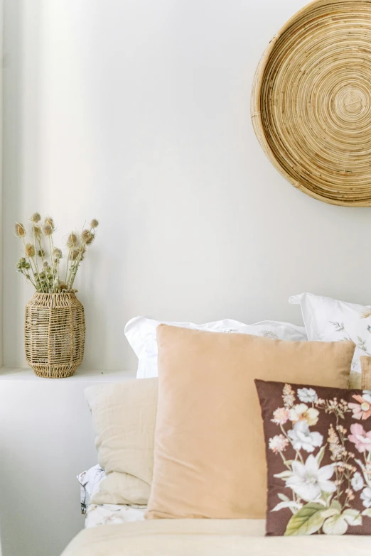 a bed room with a neatly made bed and a basket on the wall, inspired by Riad Beyrouti, trending on unsplash, light and space, brown flowers, detail shot, white background, cushions