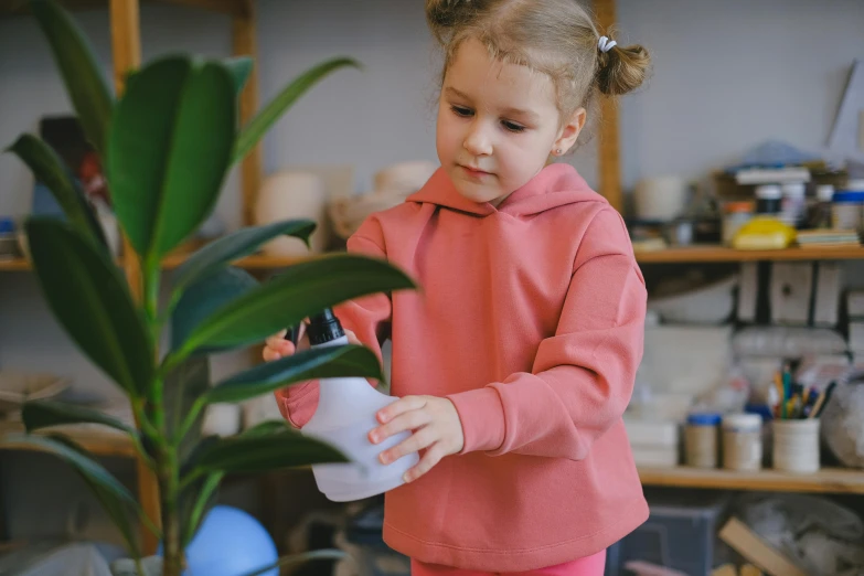 a little girl standing next to a potted plant, pexels contest winner, wearing a track suit, she is in the potions workshop, thumbnail, pink