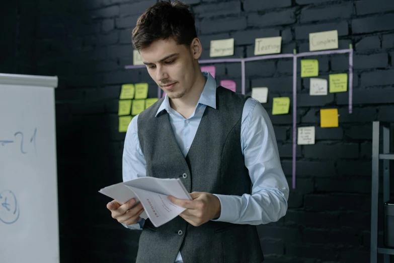 a man standing in front of a whiteboard holding a piece of paper, pexels contest winner, it specialist, concentrated, killian eng, formal attire