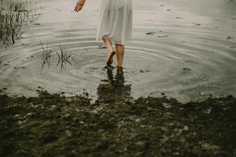 a woman in a white dress standing in a body of water, an album cover, pexels contest winner, algae feet, ash thorp, promo image, rainfall and mud