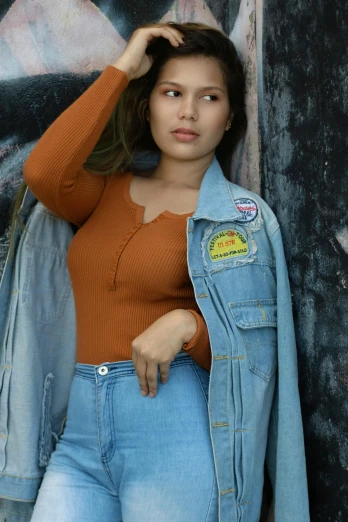 a woman in jeans leaning against a wall, an album cover, inspired by Elsa Bleda, trending on pexels, photorealism, young himalayan woman, round-cropped, avatar image, caramel. rugged