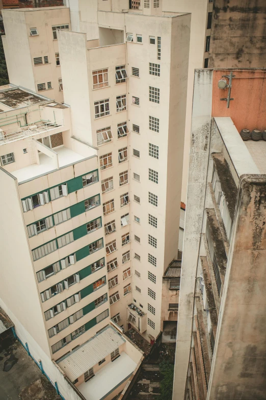 a couple of tall buildings next to each other, a tilt shift photo, trending on unsplash, modernism, an abandonded courtyard, hong kong 1 9 5 4, balconies, high angle shot