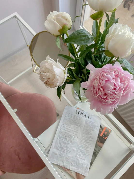 a vase filled with flowers sitting on top of a table, a picture, vogue magazine style, detailed product image, white and light-pink outfit, reading a newspaper