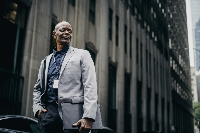 a man in a suit standing in front of a building, pexels contest winner, grey skinned, black man, people at work, 5 0 years old man