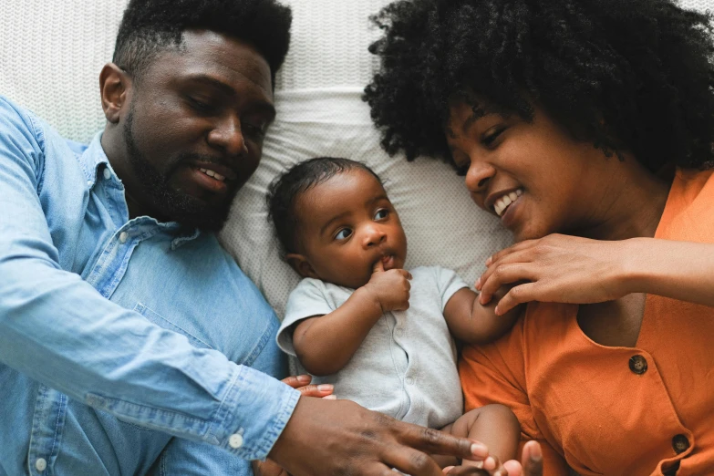 a man and woman laying on a bed with a baby, pexels contest winner, panel of black, cute and lovely, touching heads, coloured