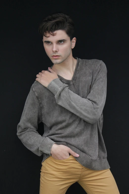 a man standing in front of a black background, an album cover, pexels contest winner, wearing casual sweater, washed out colors, pale skin!, model pose