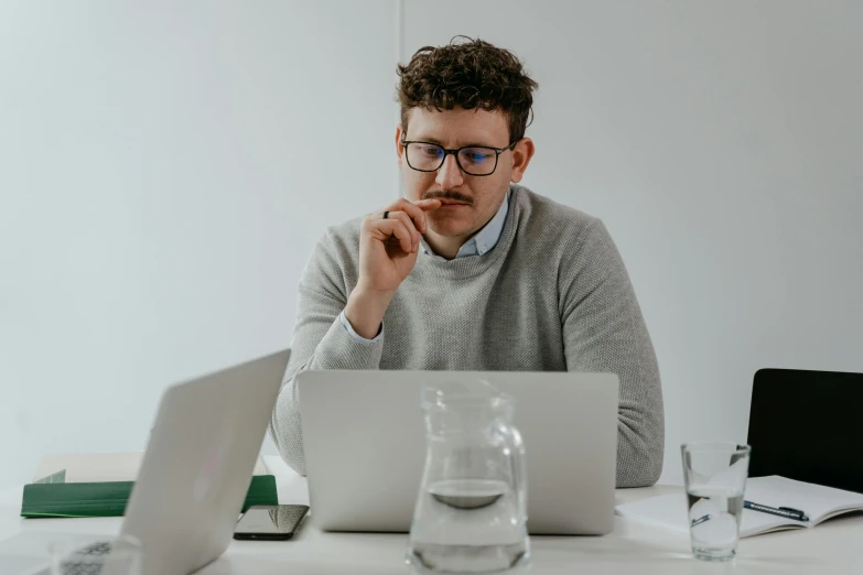 a man sitting at a table with a laptop, lachlan bailey, concentration, avatar image, barely visible