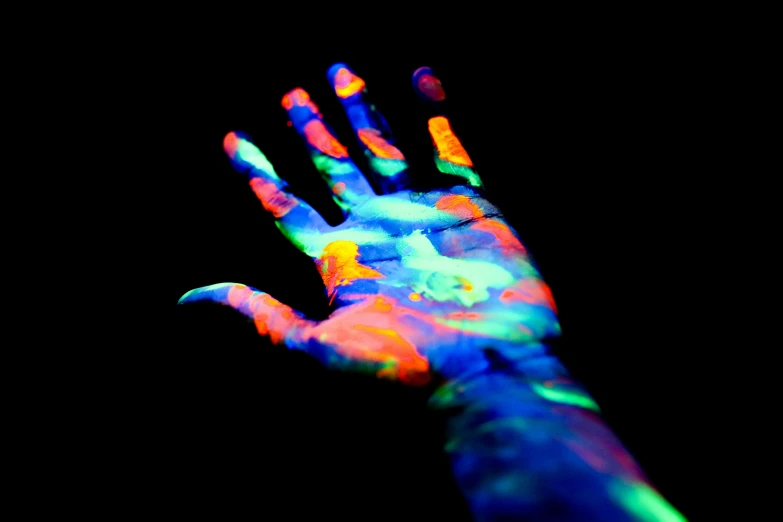 a close up of a person's hand with fluorescent paint on it, a hologram, inspired by Emil Nolde, pexels, human arms, color slide, multi colour, bright on black