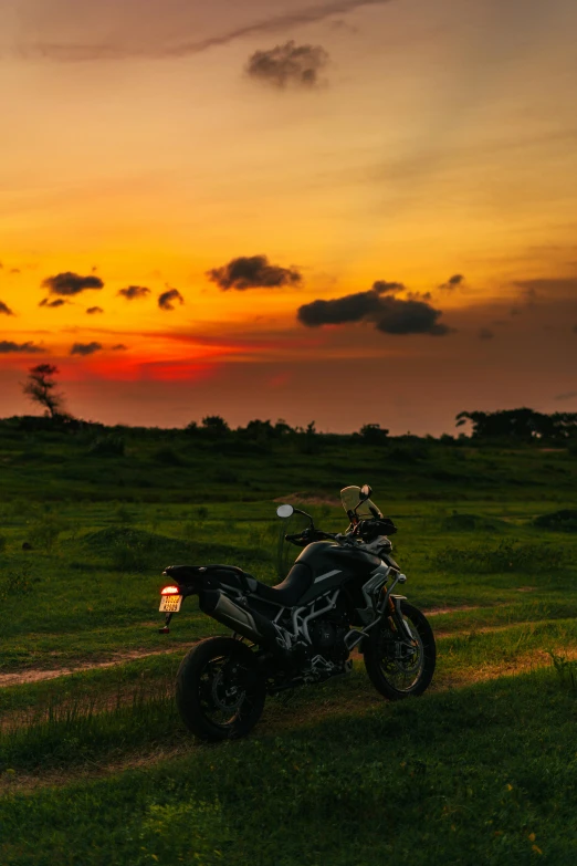 a motorcycle parked on the side of a dirt road, by Daniel Seghers, pexels contest winner, sunset sky, sri lanka, a green, black