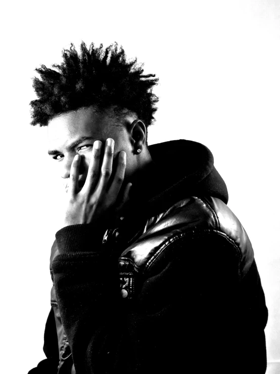 a black and white photo of a man talking on a cell phone, an album cover, inspired by Xanthus Russell Smith, vanitas, wild spiky black saiyan hair, profile picture 1024px, looking from shoulder, black teenage boy
